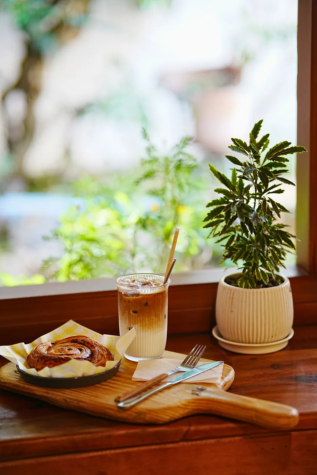 Bạc xỉu và bánh croissant trên bàn cạnh cửa sổ
